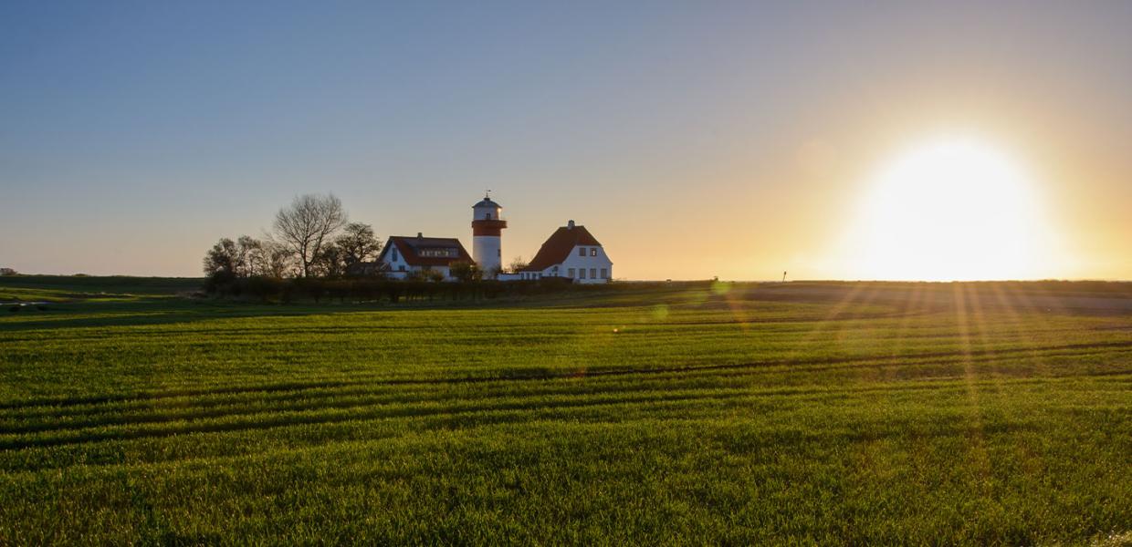 Solen står op på en dejlig forårsdag på Langeland og skinner over de grønner marker og fyrtårnet ved Hou,